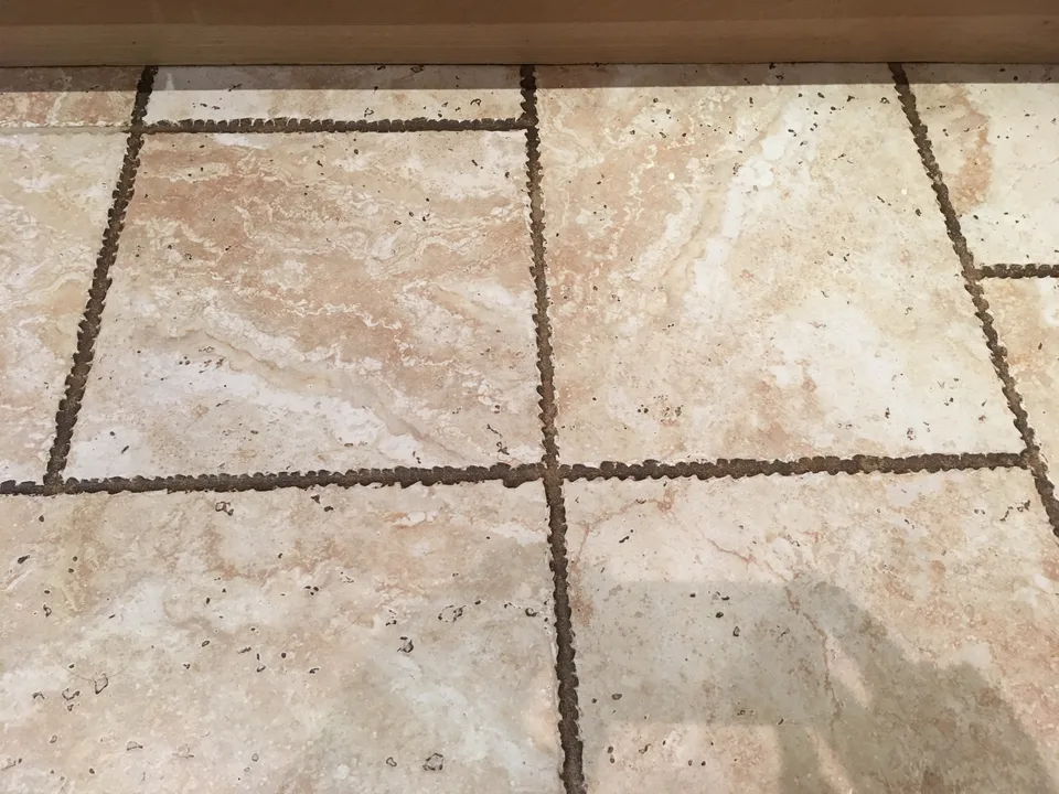 Ceramic tiled floor before professional cleaning, with dark, dirty grout lines