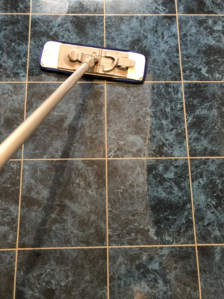 Floor-care mop working across dark Karndean tiles during a kitchen floor renewal